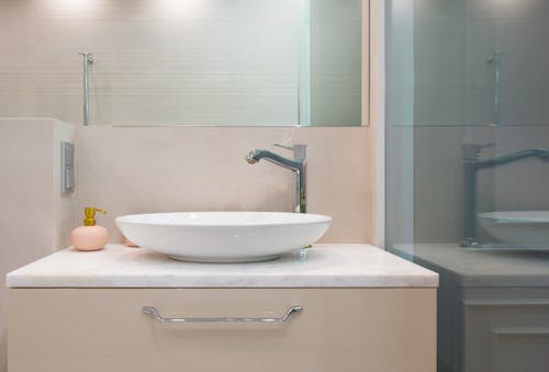 Restroom interior with sink and tap on counter near mirror