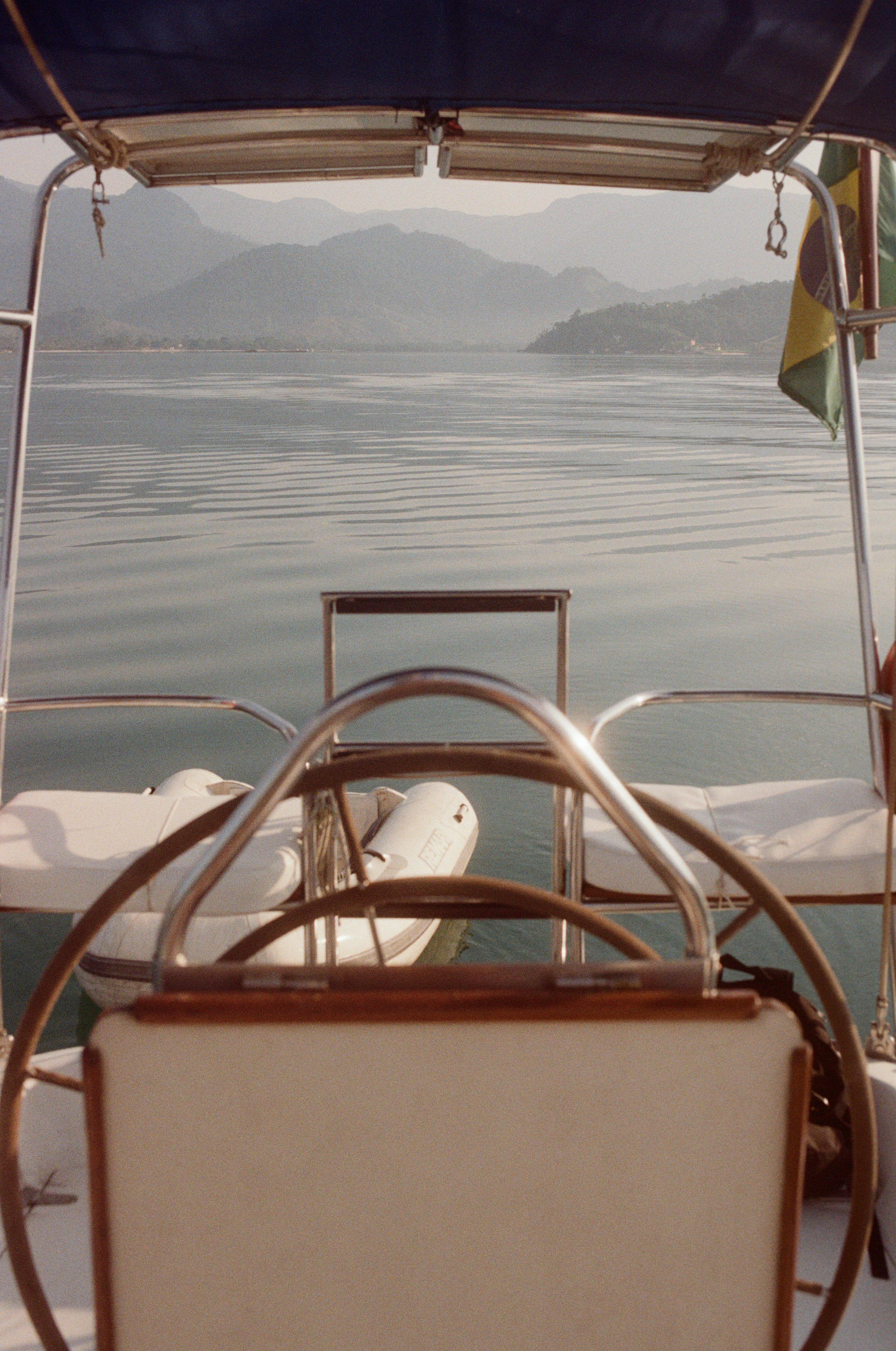 Yacht with boat sailing on rippling water of pond surrounded by hills in haze