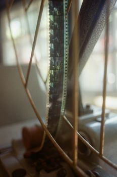 Old fashioned round metal bobina with tape of vintage pictures in photo development workshop