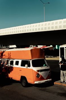 Retro orange bus parked under a bridge in Puebla, Mexico, capturing a nostalgic travel scene.