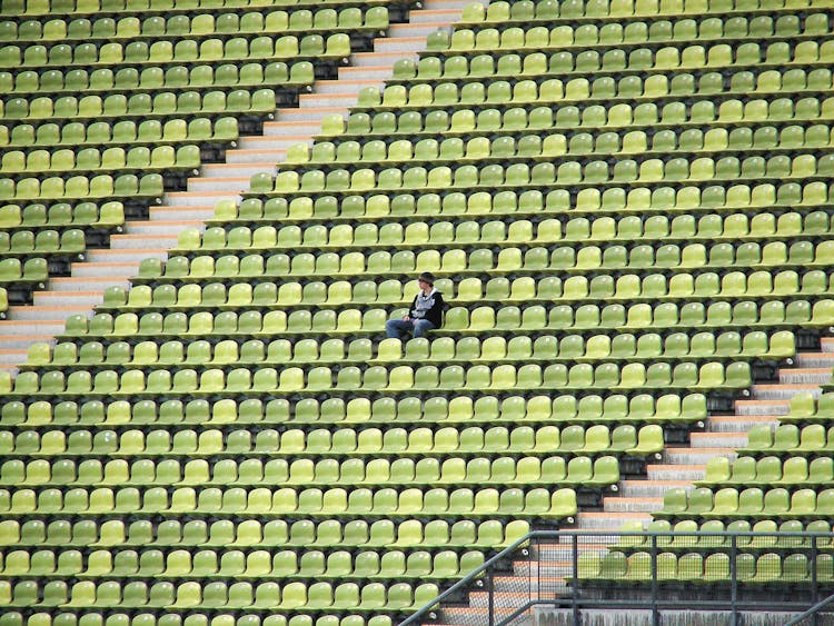 Woman In Grey Shirt Sitting On Stadium Chair