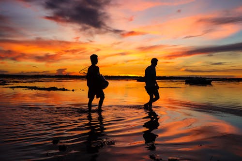 Silhouette of Two Men On Water At Sunset