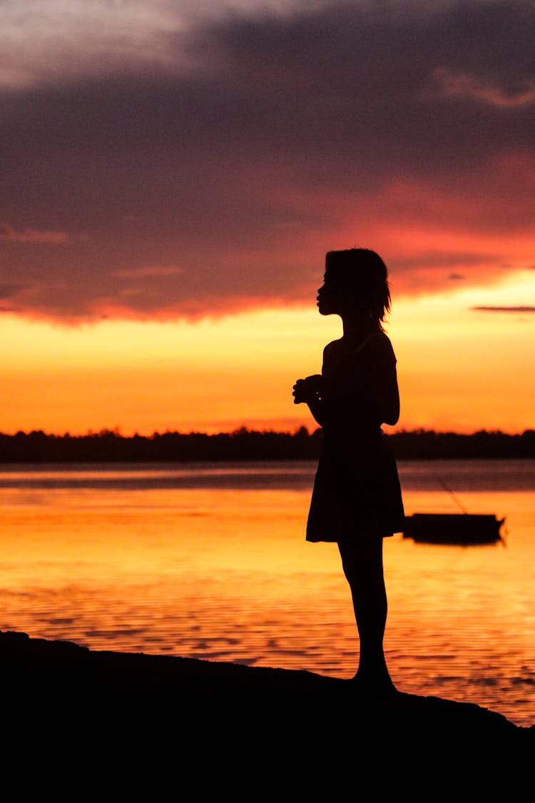 Silhouette Of A Girl Standing On The Beach During Sunset