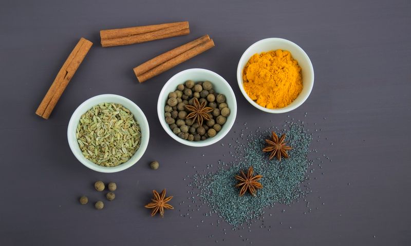 Especiarias aromáticas em tigelas de cerâmica branca sobre superfície de madeira