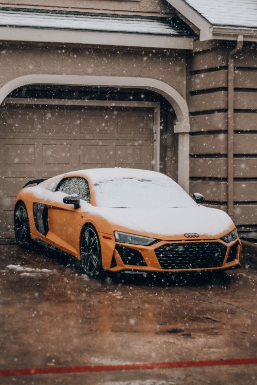 Free Luxury sports car covered in snow parked in a driveway during winter snowfall. Stock Photo