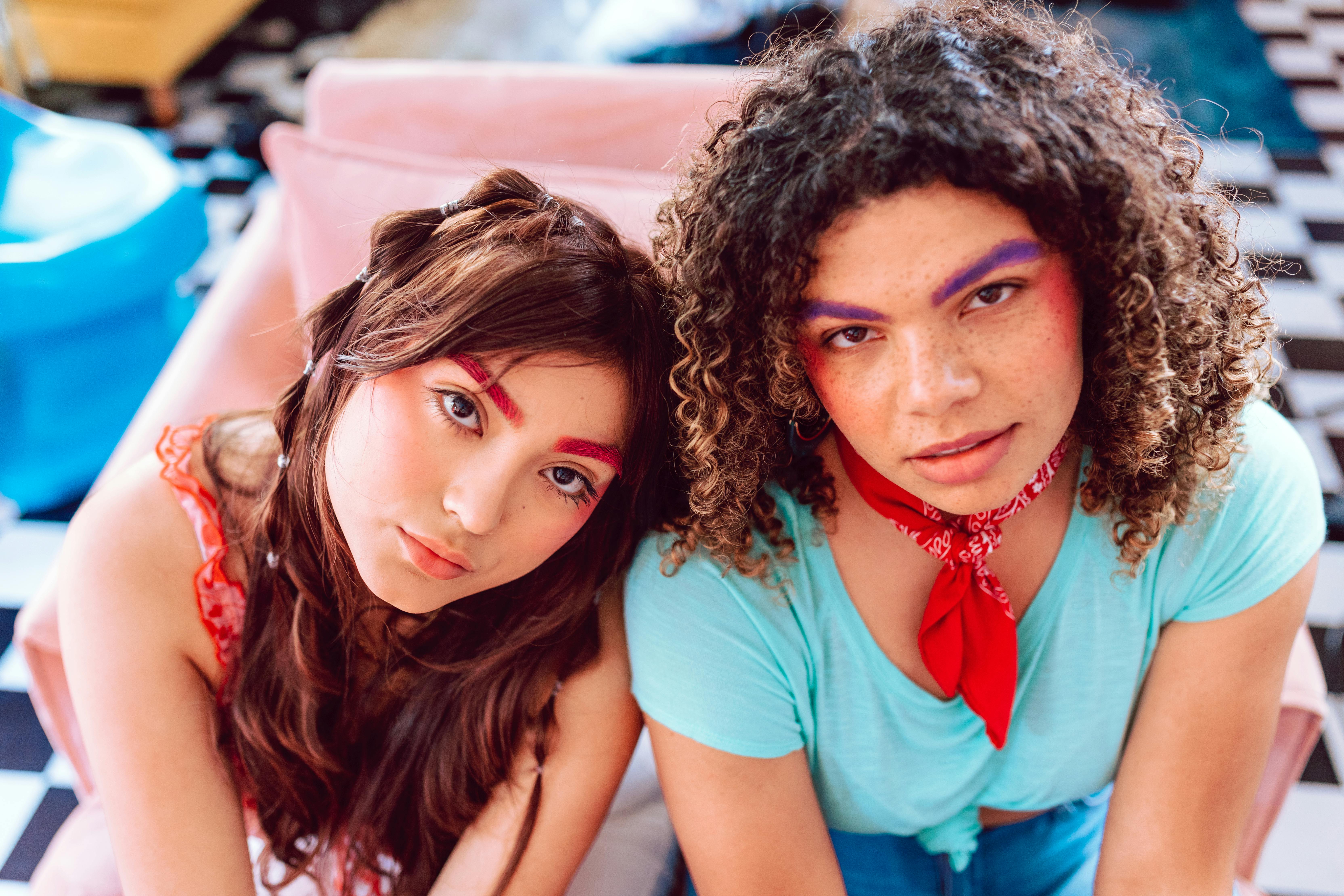 young women sitting beside each other while posing at the camera