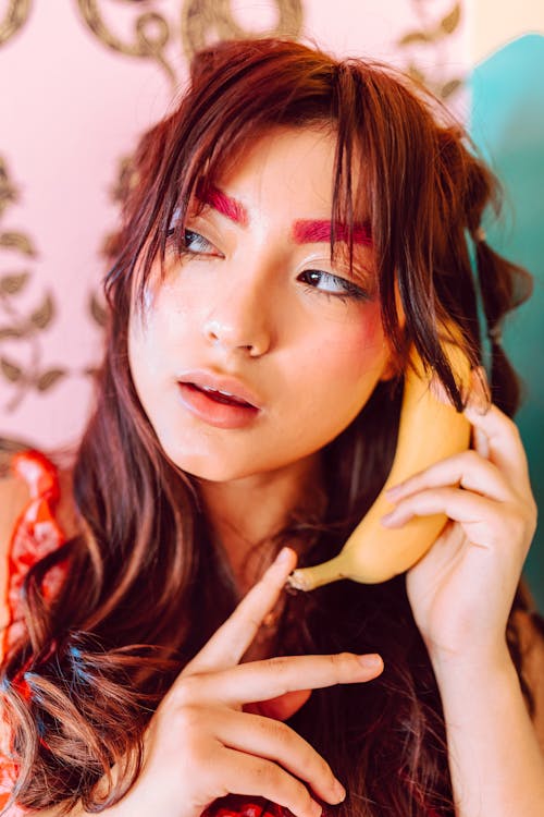 Free Woman Holding a Banana near Her Ear Stock Photo