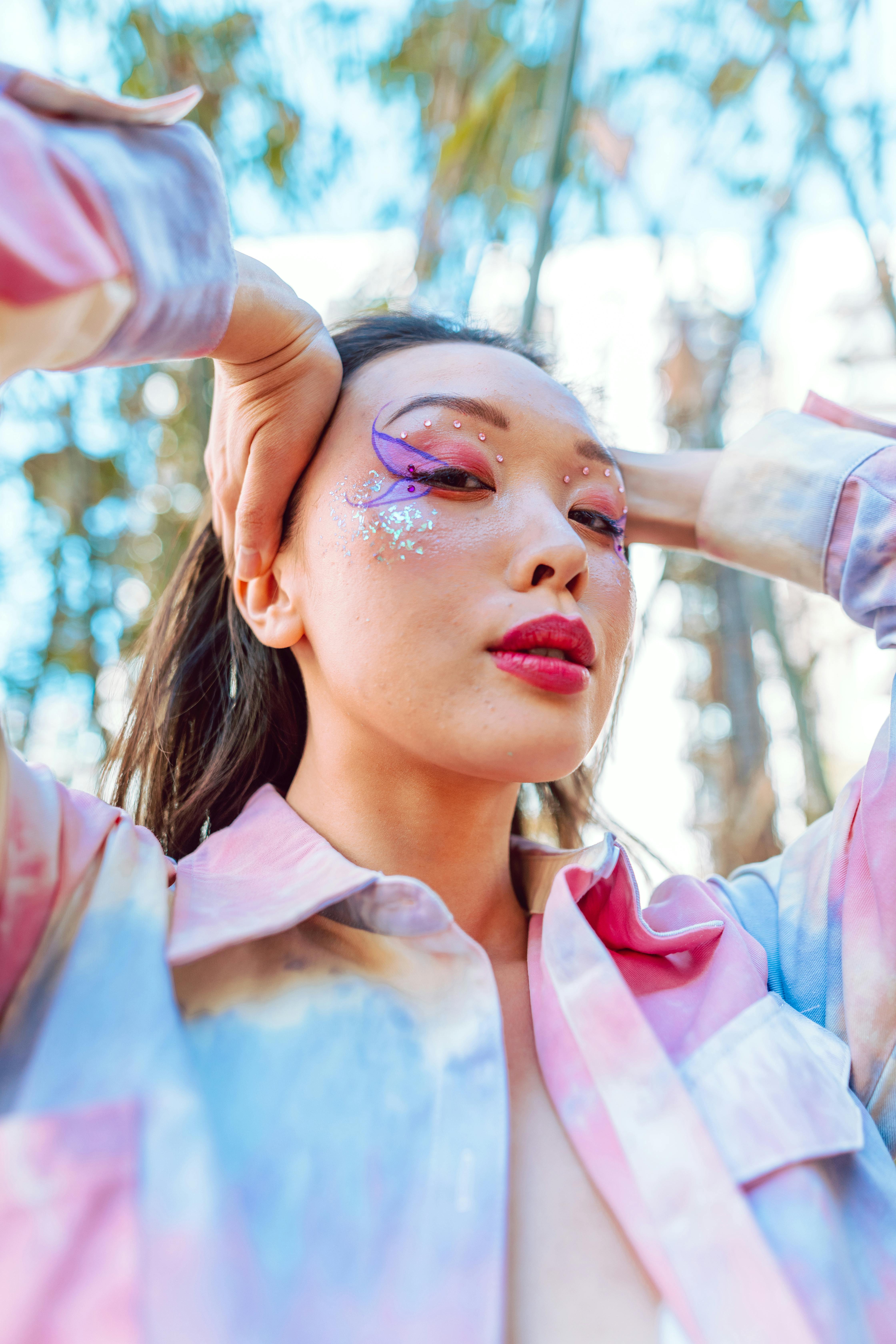 Colorful portrait of a woman with artistic makeup posing outdoors.