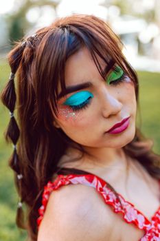 Close-up portrait of a woman with vibrant makeup featuring bold eyeshadow and pink lipstick.