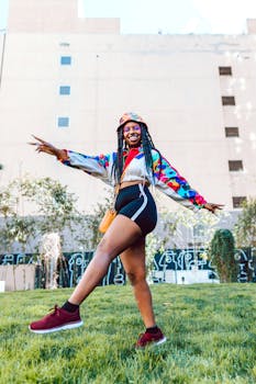 Cheerful young woman poses stylishly outdoors, embracing colorful street fashion.