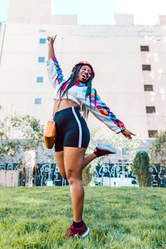 Young woman with braided hair and colorful outfit energetically jumping in an urban park.