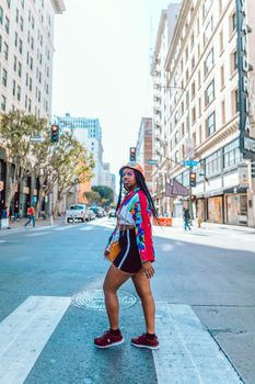 Stylish young woman confidently walks through a busy city intersection.