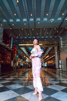 Confident woman in fashionable attire under string lights in an indoor space