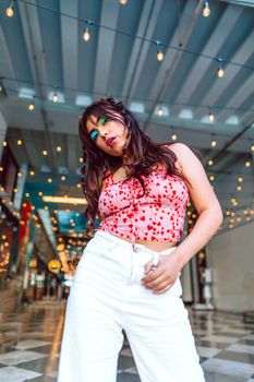 Vibrant portrait of a young woman with colorful makeup and trendy outfit in an urban environment.