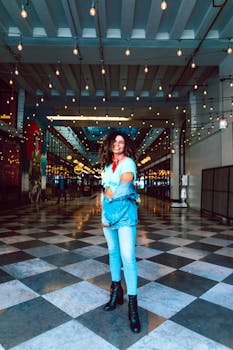 Fashionable woman poses confidently in a modern illuminated hallway.