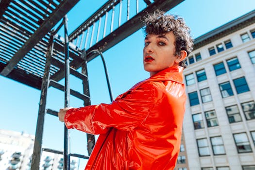 Stylish individual in vibrant red jacket poses on a fire escape, embodying urban cool.