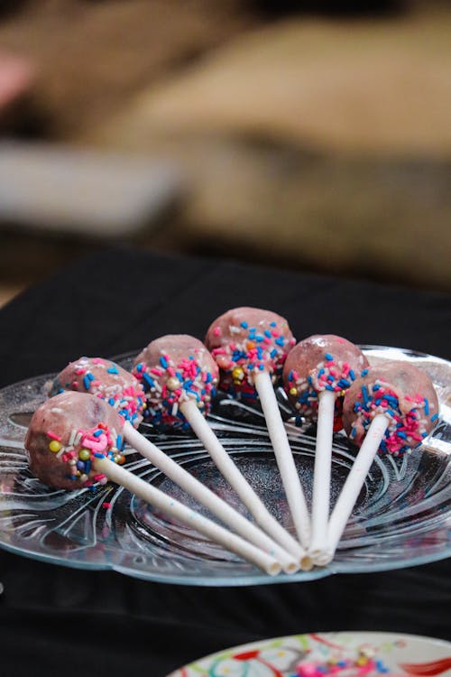 Free Selective Focus Photo of Lollipops with Sprinkles on a Glass Plate Stock Photo
