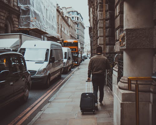 Free Man in Brown Jacket Holding Black Travel Luggage Stock Photo