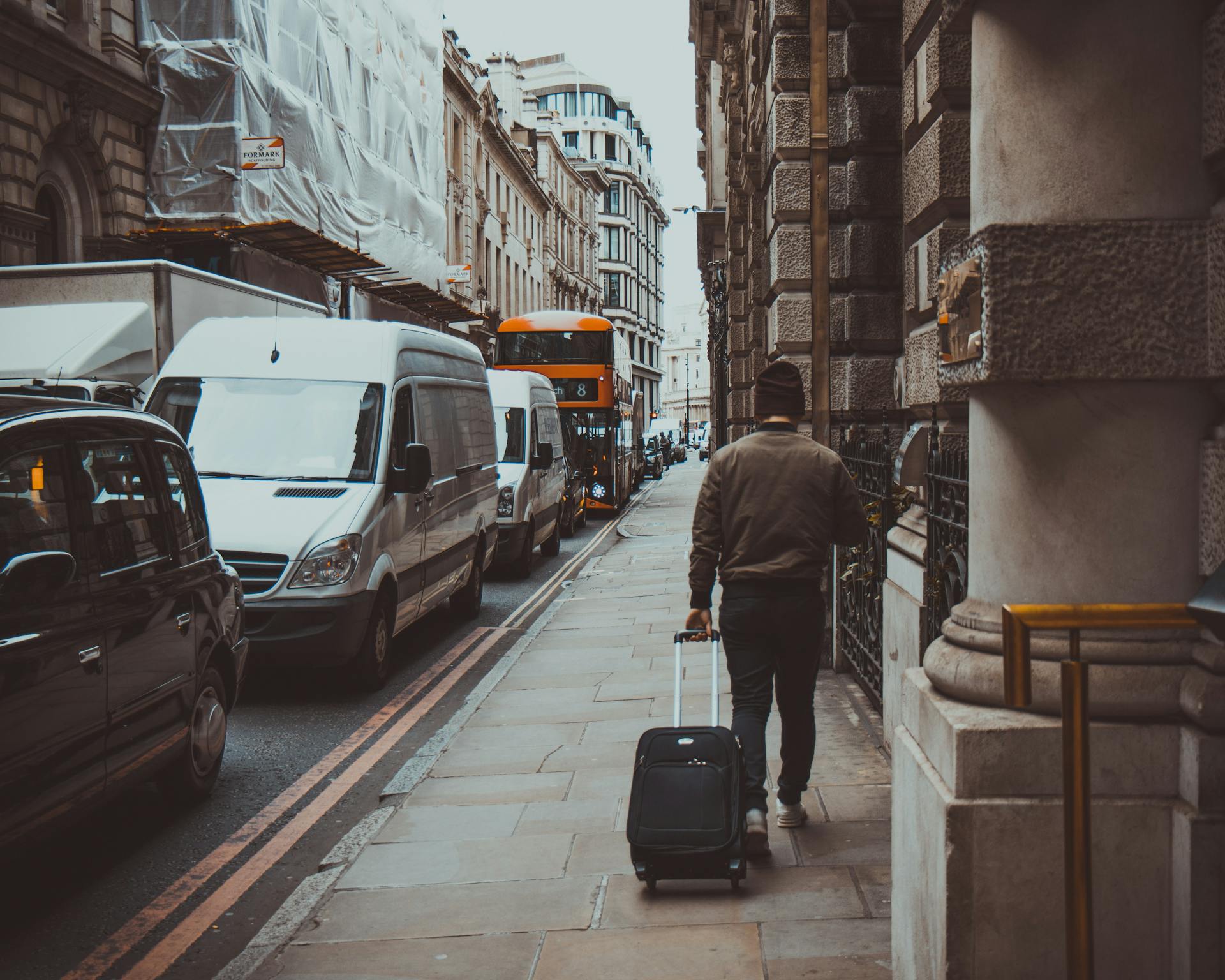 Man in Brown Jacket Holding Black Travel Luggage