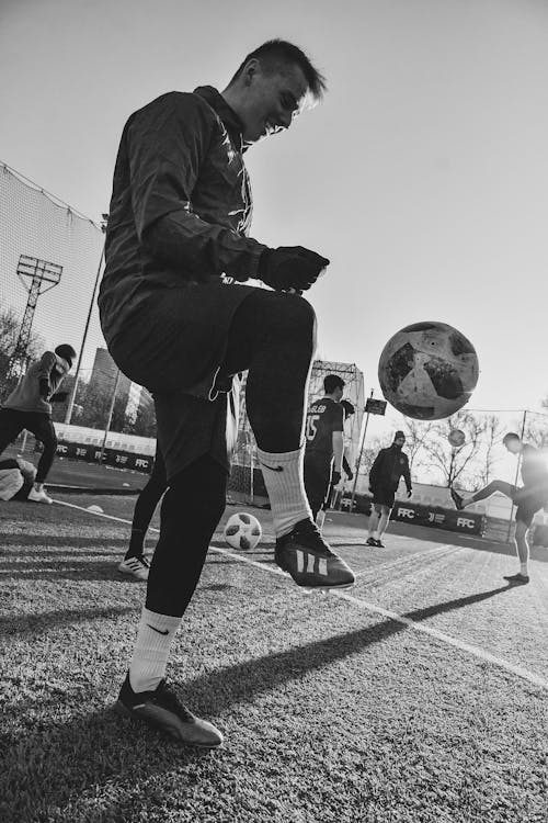 Grayscale Photo of a Man Playing Soccer