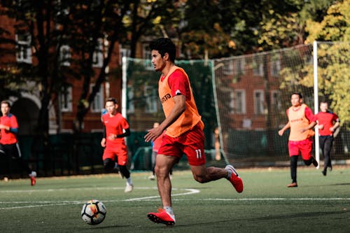 Selective Focus Photo of an Athlete in a Red Shirt Playing Soccer