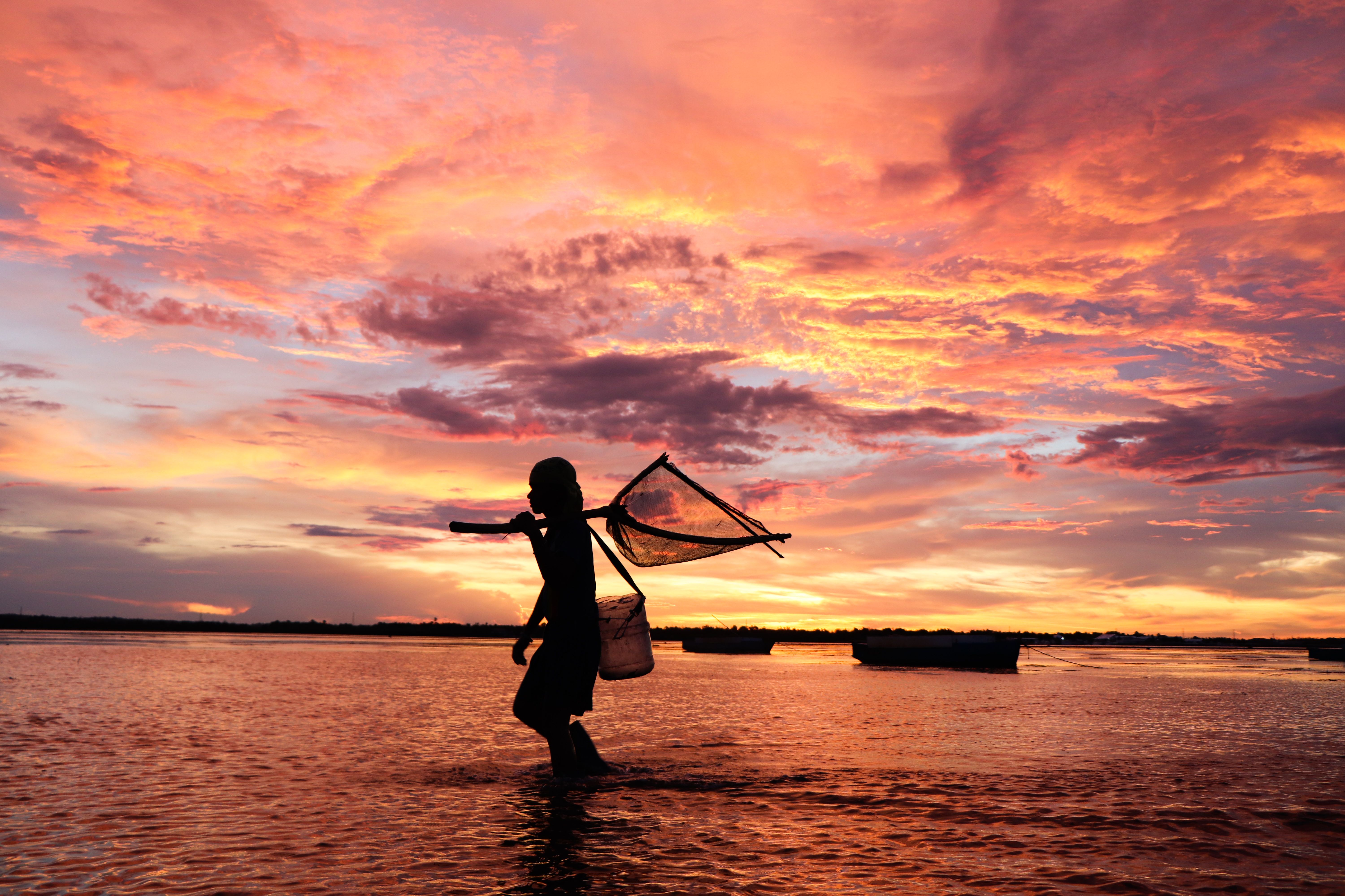Silhouette of a girl walking on water with fish net, Madagascar