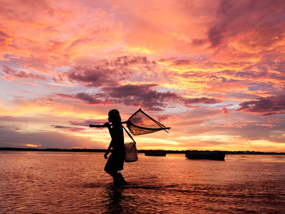Silhouette of a girl walking on water with fish net, Madagascar