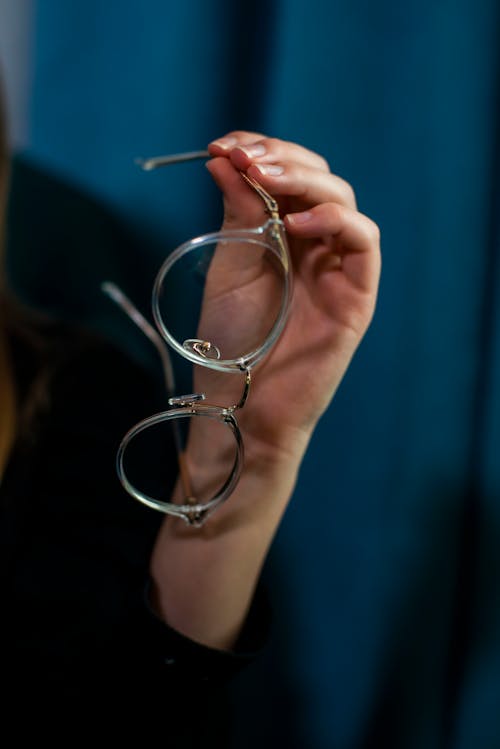 Free Photo of a Person's Hand Holding Clear Eyeglasses Stock Photo