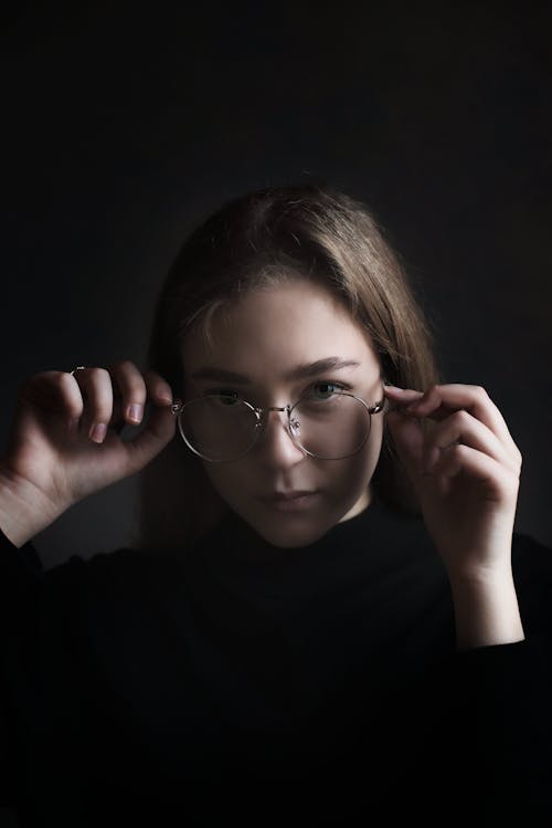Portrait of a Woman Touching Her Eyeglasses While Looking at the Camera
