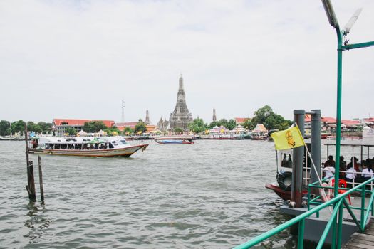 Explore the bustling river life with Wat Arun in the background, capturing Bangkok's cultural essence.
