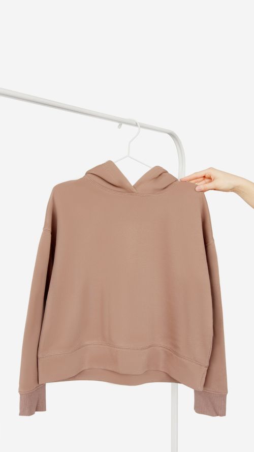 A soft beige brushed-cotton hooded top on a hanger. Photo by Artem Podrez on Pexels.