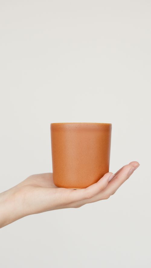 Free A minimalist terracotta pot held on a person's open palm against a neutral background, showcasing simplicity and design. Stock Photo