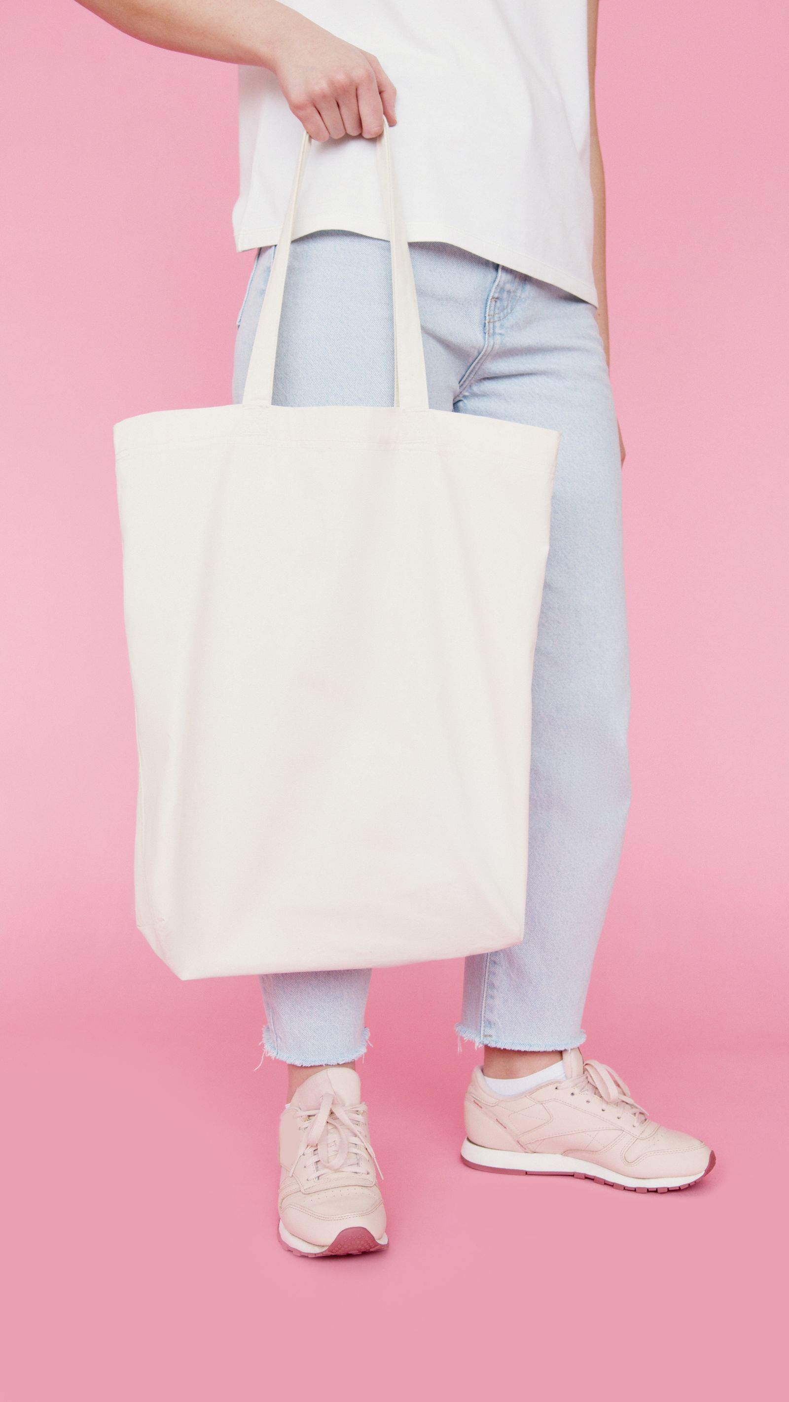 Plain unbranded canvas tote bag held at the side, illustrating tote-style bag carry