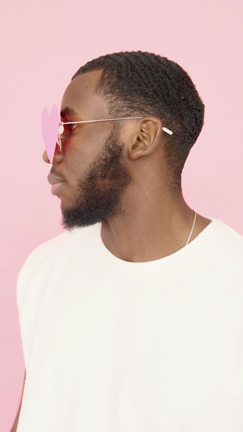 Free A fashionable man in a white t-shirt with heart-shaped sunglasses on a pink backdrop. Stock Photo