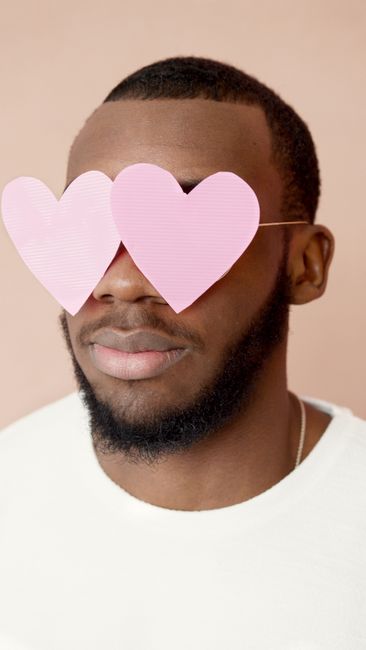 African American man wearing pink heart-shaped glasses, symbolizing love and affection.