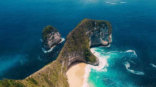Free Green rocky cliff jutting into turquoise ocean Stock Photo