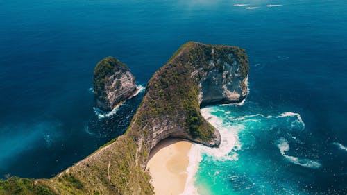 Green rocky cliff jutting into turquoise ocean