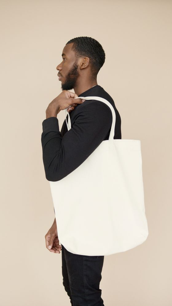 Man carrying a plain white tote bag, photo by Artem Podrez on Pexels