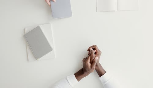 Free Hands on White Surface Near Blank Notebook Stock Photo