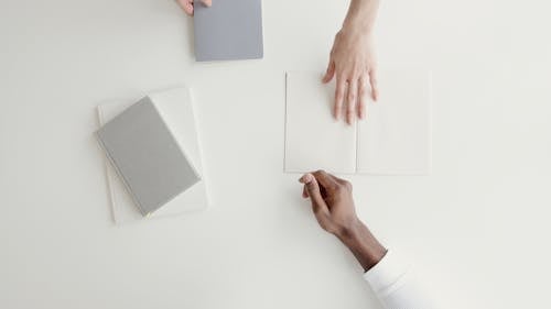 Person Handing A White Paper To Another Person