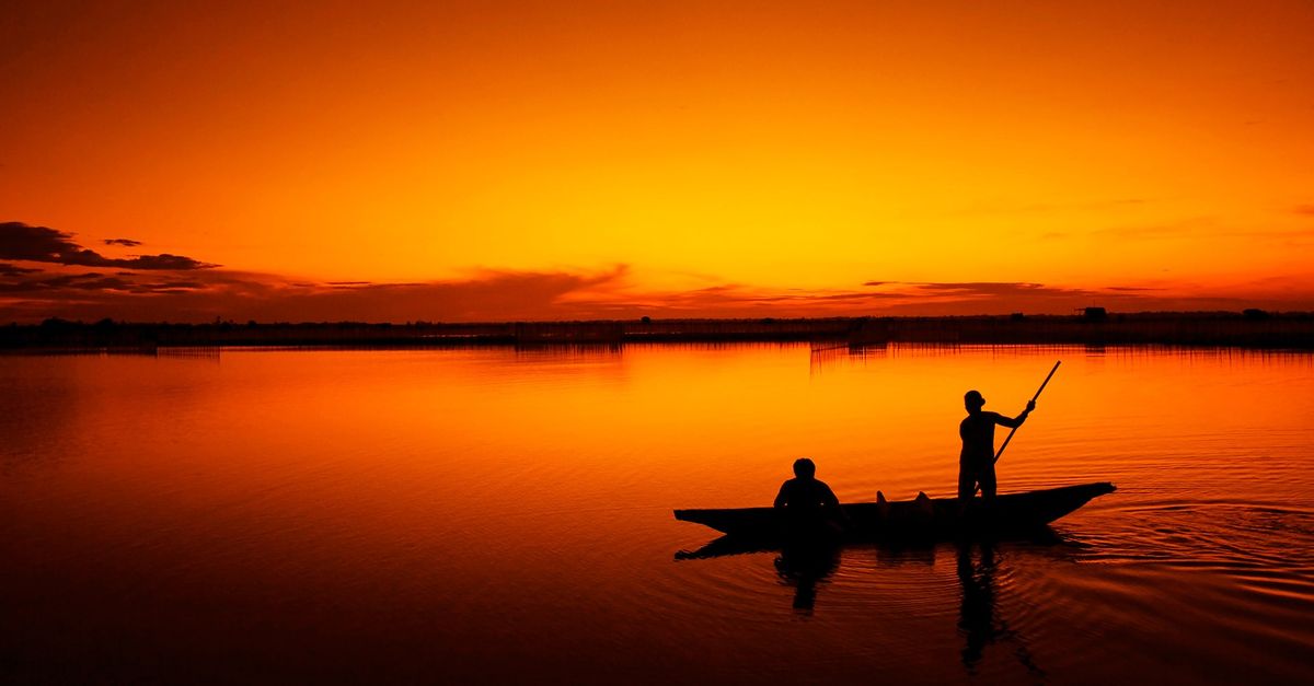 A dugout canoe on Lake Volta at sunset with silhouetted mountains
