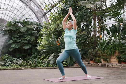 Elderly woman performing yoga pose in a serene botanical greenhouse, promoting relaxation and wellness.