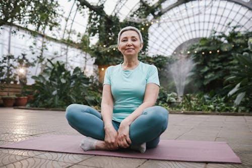 Woman Sitting on a Yoga Mat While Smiling