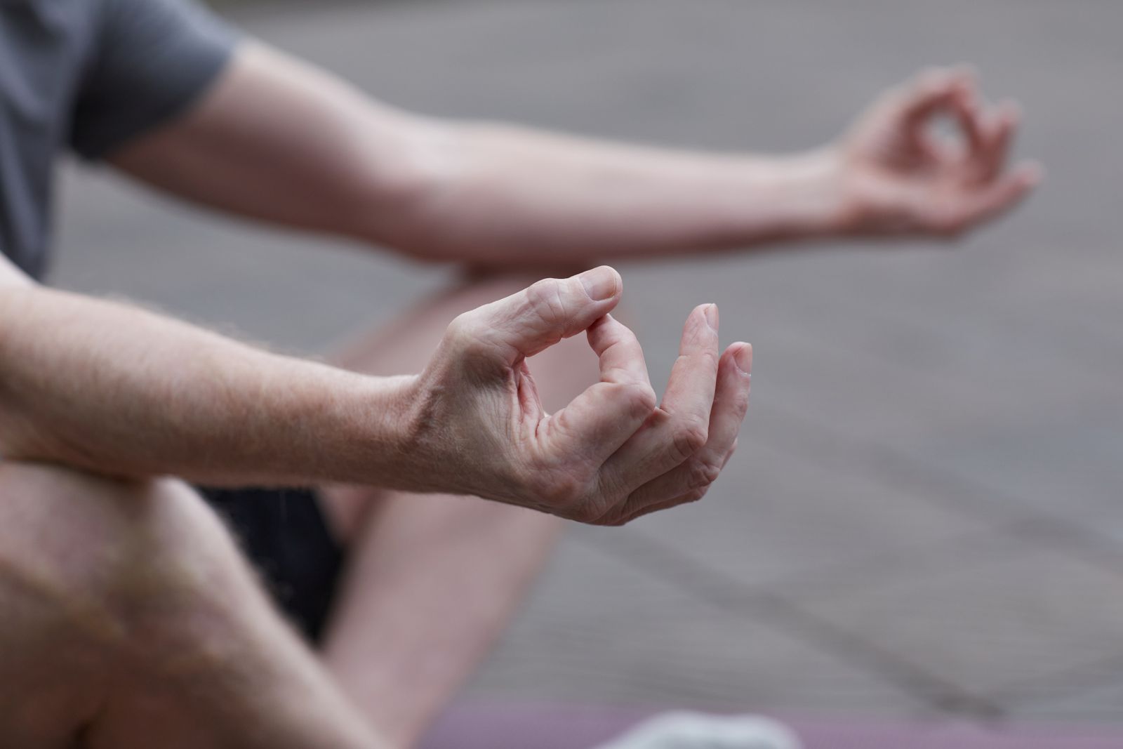 Close-up of hands in a gentle meditation pose outdoors, representing the yoga principle of ahimsa or non-violence