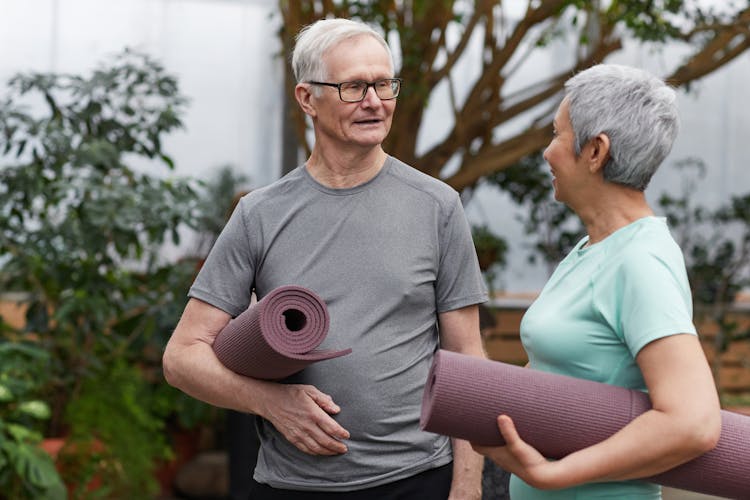 Couple Holding Yoga Mats While Looking At Each Other