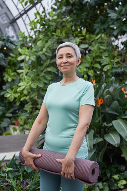 Femme souriant tout en tenant un tapis de yoga