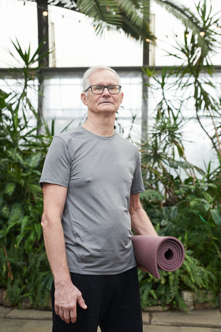 Man Standing While Holding A Yoga Mat