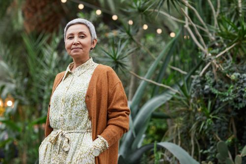 Free Senior woman in a stylish outfit enjoying a peaceful garden setting. Stock Photo