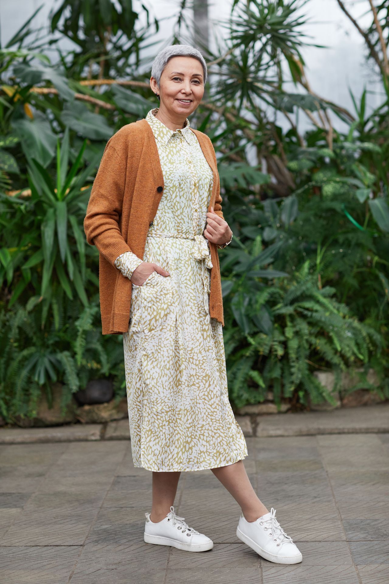 Older woman wearing a patterned shirt dress with a rust-colored cardigan