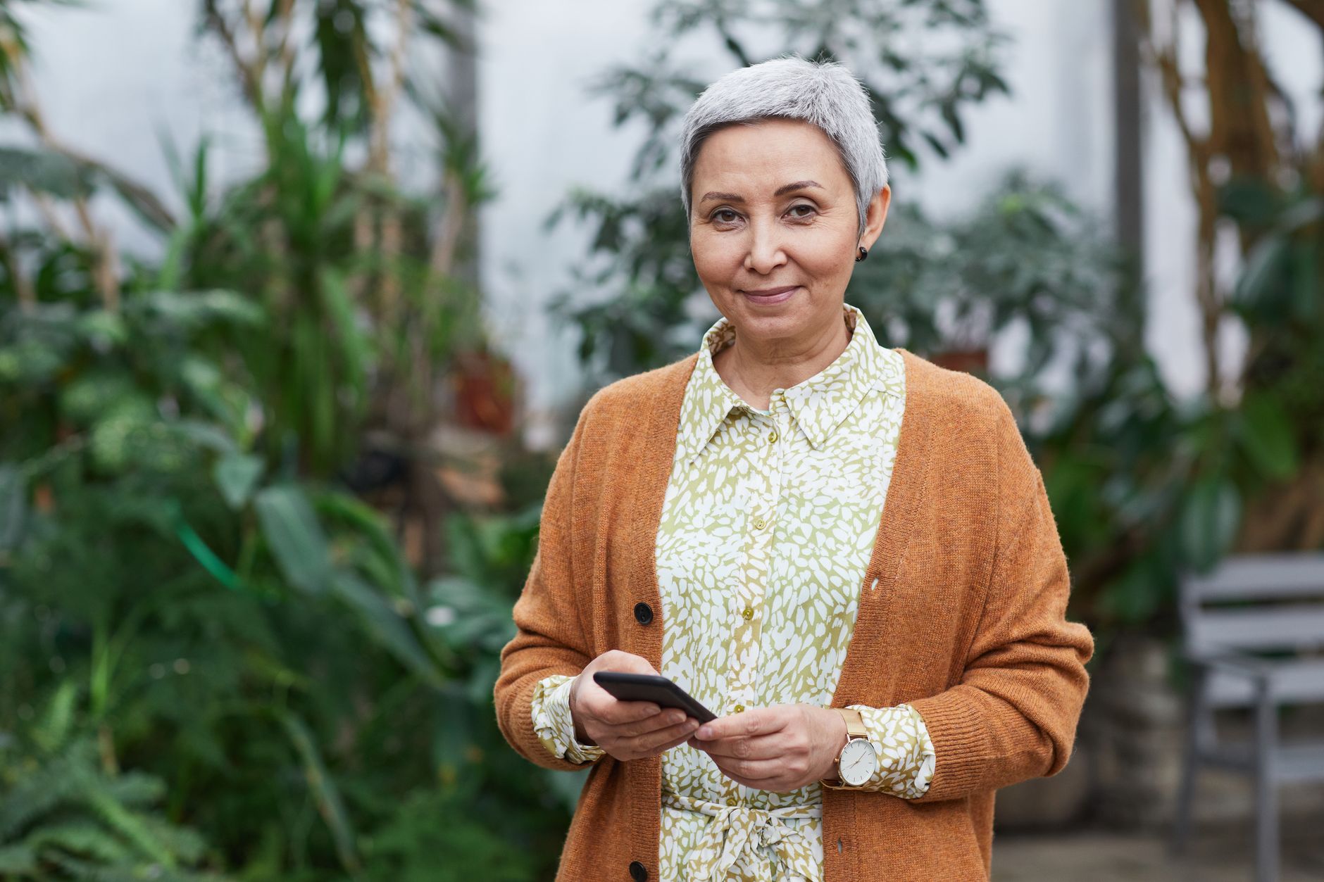 전남 어르신 스마트폰 무료 교육, 섬·농촌 지역까지 무료 교육 찾는 법 2 Elderly woman with smartphone standing in a greenhouse, smiling.